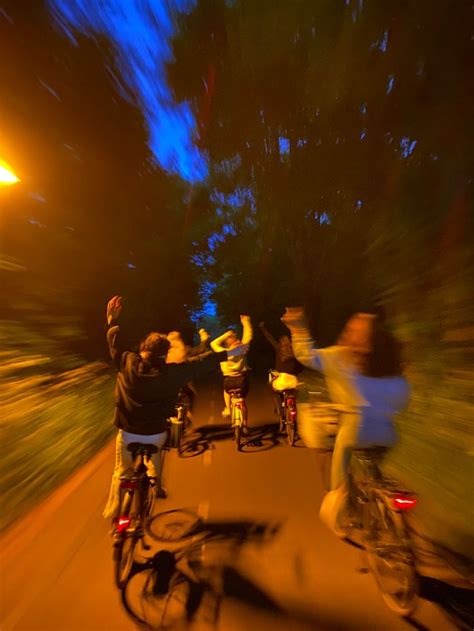 Friends Riding A Bike At Night Throwing Their Hands In The Air Night