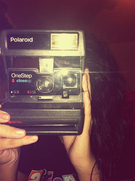 A Woman Holding An Old Polaroid Camera Up To Her Face