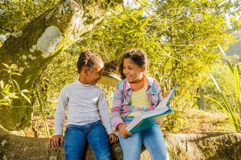 Jeunes Sœurs Avec Un Livre Assis Sur Un Arbre Photo Gratuite