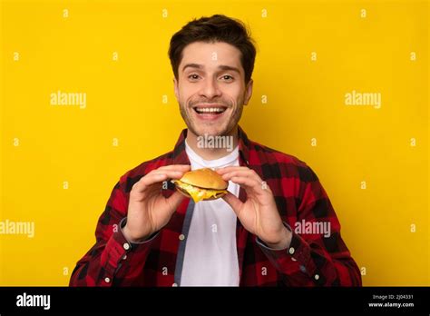 Smiling Young Guy Holding Burger At Studio Stock Photo Alamy