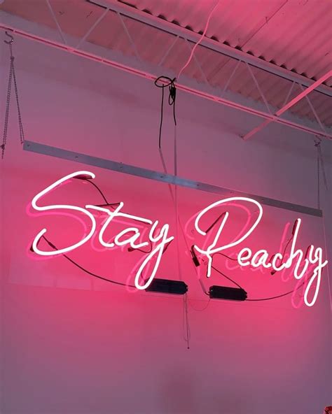 A Neon Sign That Says Stay Peachy Hanging From The Side Of A Pink Wall