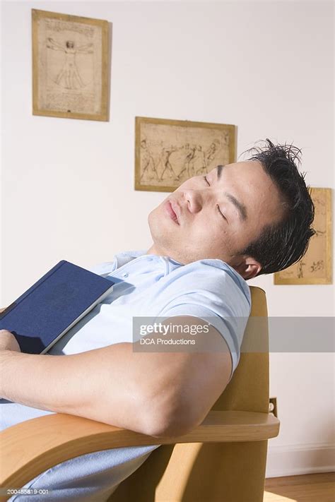 Young Man Sleeping In Chair With Book On Chest High Res Stock Photo