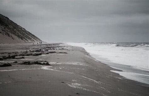 People Walking Along The Beach On An Overcast Day With Waves Crashing