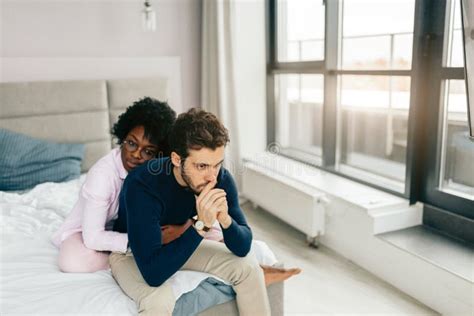 Attractive African Girl Comforting Her Upset Boyfriend On Sofa At Home