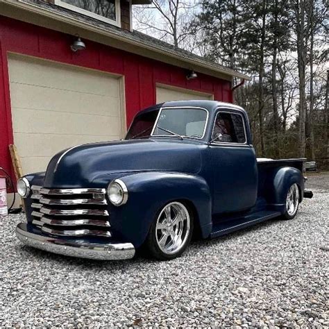 An Old Blue Truck Parked In Front Of A Garage