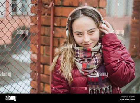 Happy young woman with Down syndrome listening to music in town in winter Stock Photo - Alamy