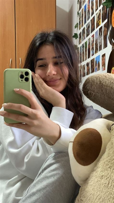 A Woman Is Holding Her Cell Phone While Sitting On The Couch With A Teddy Bear