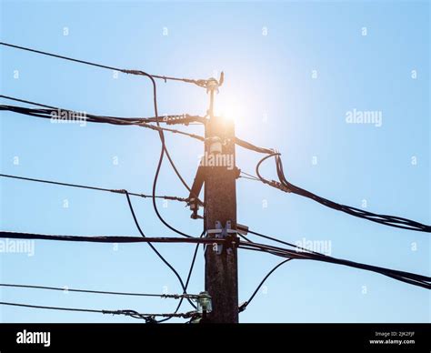 Iron Electric Pole With Wires With Solar Backlight Against The Blue Sky