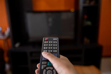 Premium Photo Hand With Remote Control Pointing At The Television