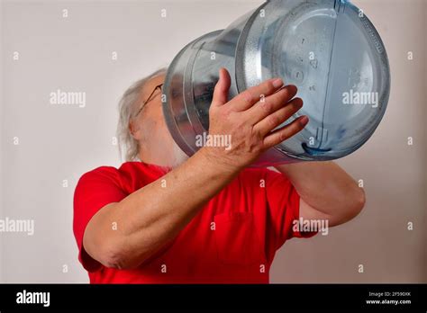 Elderly Male Trying To Drink Water From A Huge Water Gallon Stock Photo