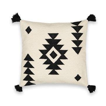 A Black And White Pillow With Tassels On The Front Sitting On A White