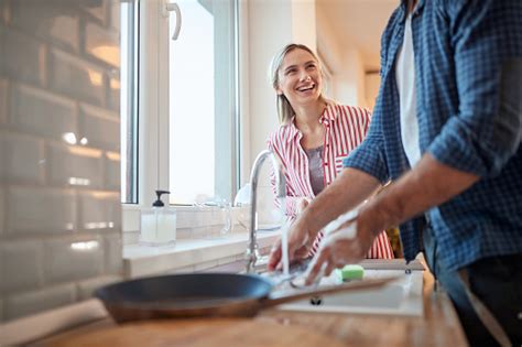 A Young Couple Enjoying Doing Housework In The Kitchen Together Kitchen