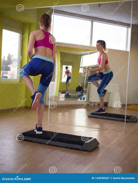 Young Model Girl Makes Exercises at the Gym in Front of Mirror Stock