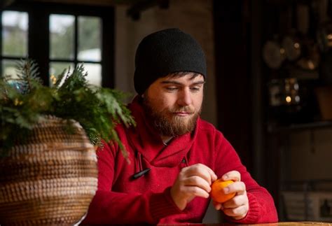 Premium Photo A Man In A Hat And Sweater Eats A Tangerine