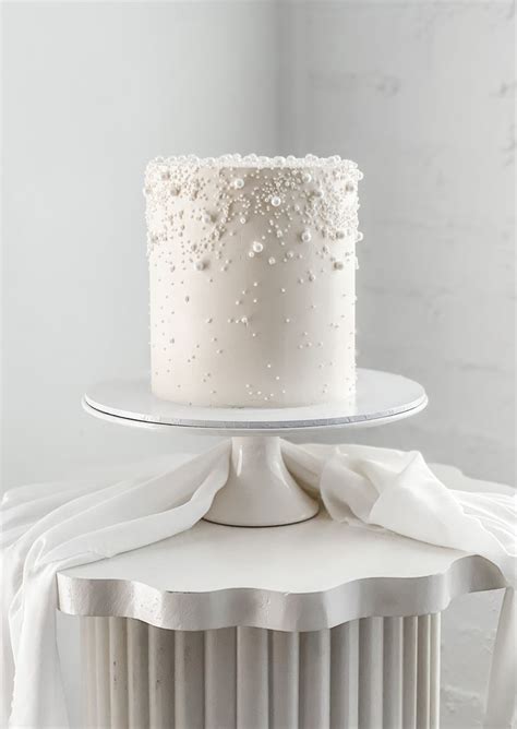 A White Cake Sitting On Top Of A Table Next To A Plate With A Napkin