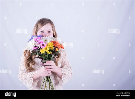 Twelve Year Old Girl With Long Dirty Blonde Hair Holding Colorful Bouquet Of Daisies Over Lower