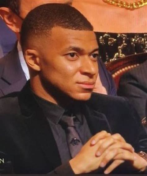 A Man In A Suit And Tie Sitting Next To Another Man With His Hand On