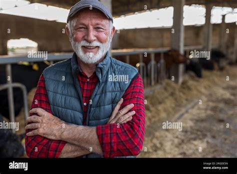 Portrait Of Mature Farmer With Crossed Arms Standing In Front Of Red