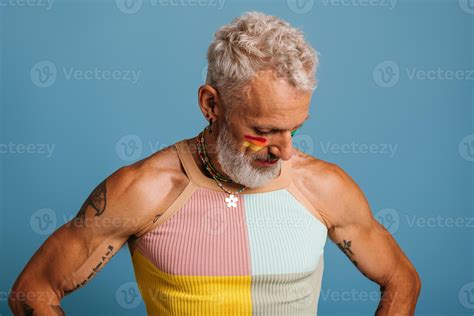 Mature Gay Man With Rainbow Flag Make Up Looking Down While Standing