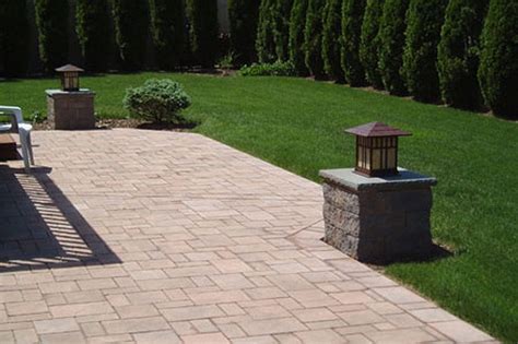 A Brick Patio With Benches And Lights In The Middle Surrounded By