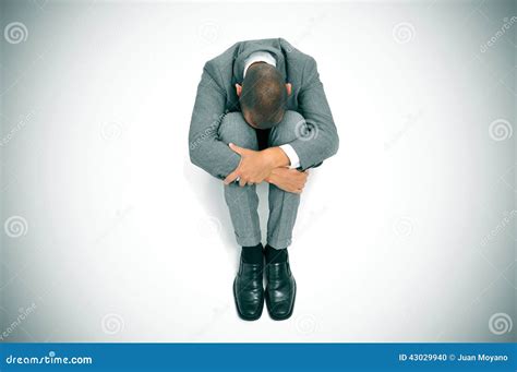 Businessman Curled Up In The Floor With His Head Between His Knees