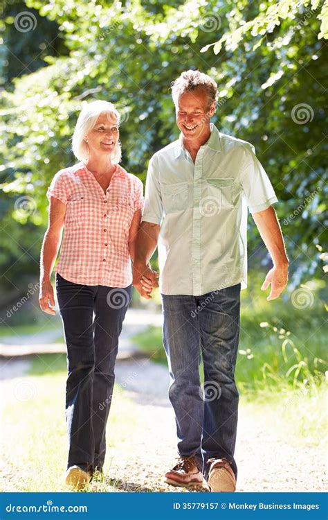 Romantic Middle Aged Couple Walking Along Countryside Path Stock Image