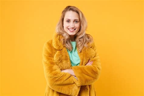 Sourire Jolie Jeune Femme Blonde Fille En Manteau De Fourrure Jaune Posant Isolé Sur Fond Orange