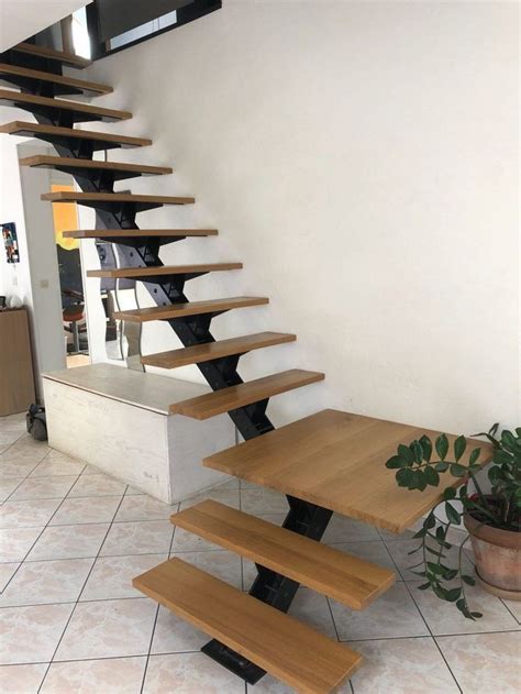 There Is A Wooden Stair Case Next To A Potted Plant On The Tile Floor