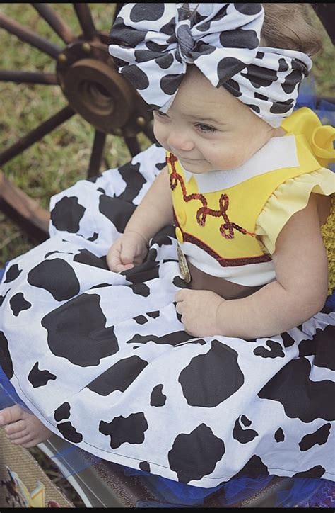 A Baby Sitting On Top Of A Chair Wearing A Cow Print Dress