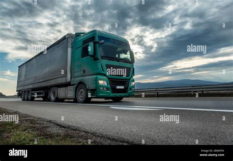 Camión semirremolque verde que conduce por una carretera con un