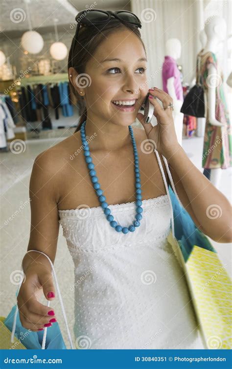 Mulher Que Usa O Telefone Celular Na Loja De Roupa Imagem De Stock