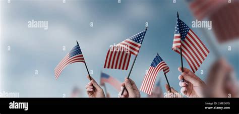 A Group Of People Holding Small Flags Of The Usa In Their Hands Stock