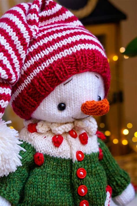 A Knitted Snowman Wearing A Red And White Hat With Pom Poms