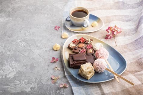 Trozos de chocolate casero con dulces de coco y una taza de café en un