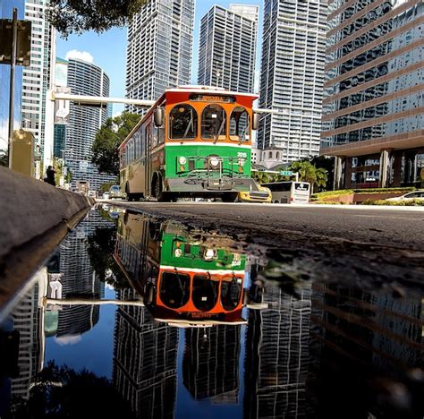 Premium Photo Bus Moving On Road Against Buildings Reflecting In Puddle