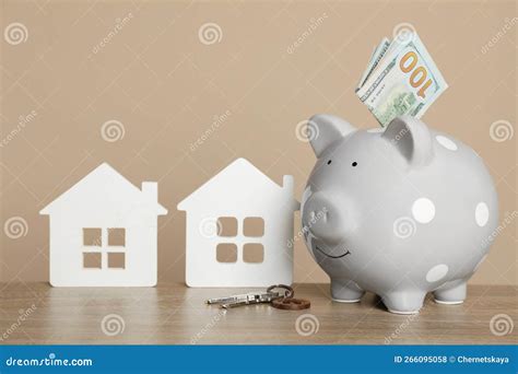 Piggy Bank Keys Dollar Banknotes And House Models On Wooden Table