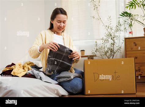 Volunteer Asian Woman Putting Unused Clothes Into Cardboard Boxes For