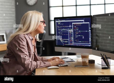 Mature Female Programmer Working With Computer At Table In Office Stock