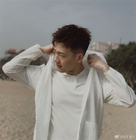 A Man Standing On Top Of A Sandy Beach Next To The Ocean Holding His Head