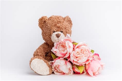 Premium Photo Teddy Bear Holding A Bouquet Of Flowers On A White