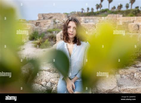 A Pensive Brunette Girl With Curly Long Hair In A White Linen Shirt