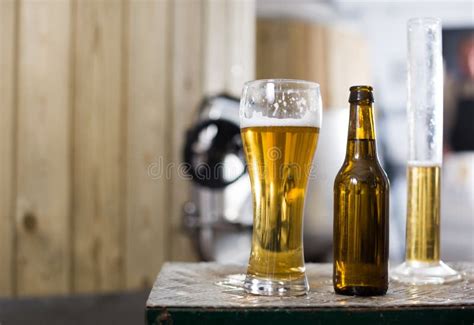 Botella Y Vidrio Con La Cerveza Del Oro En El Fondo De Los Barriles