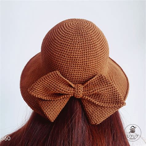 A Woman Wearing A Brown Hat With A Big Bow On Its Back Side