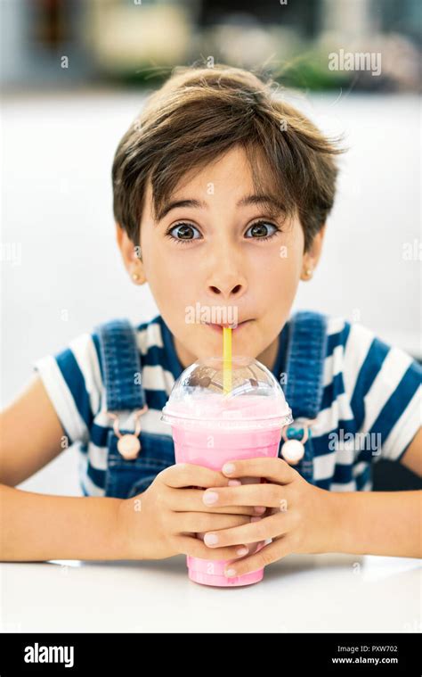 Portrait Of Little Girl Drinking Strawberry Milkshake At Pavement Cafe