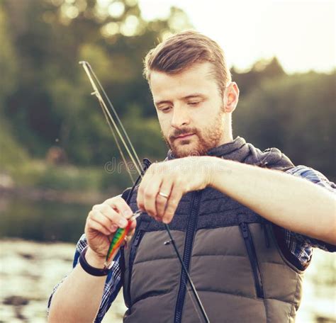 Fisherman With A Spinning And Bait Catching Fish On A Lake Or River