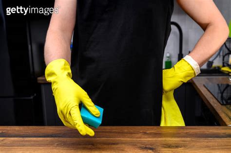 A Man Cleans The Kitchen At Home Wearing Yellow Rubber Gloves Holding