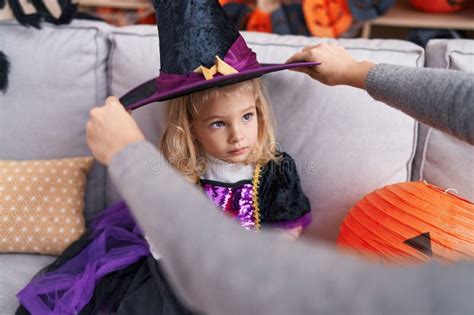Adorable Blonde Girl Wearing Hat Witch Costume Having Halloween Party At Home Stock Photo