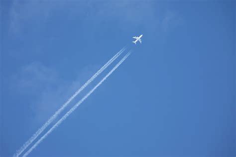 Premium Photo White Jet Airplane Flying High In The Blue Sky