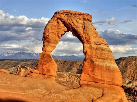 An Arch Shaped Rock Formation With Mountains In The Background