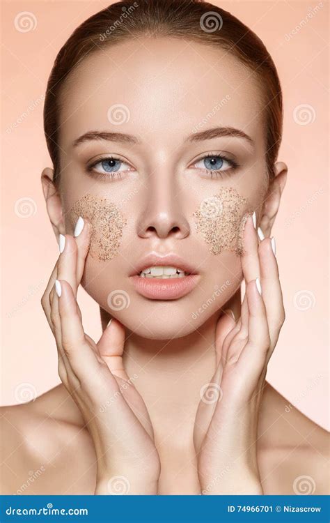 Attractive Young Girl Rubs A Skin Scrub On The Cheeks Stock Image